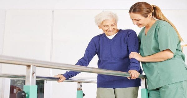 blog picture of elderly woman being helped by physical therapist nurse