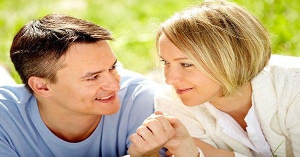 blog picture of couple laying in the grass holding hands smiling at each other