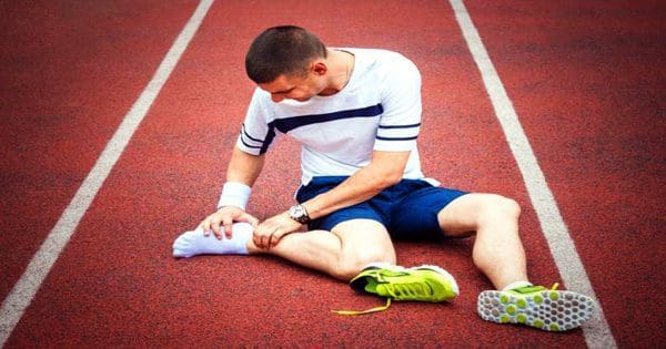 blog picture of runner on track shoe off grabbing foot in pain