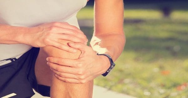 blog picture of male runner kneeling down grabbing knee with both hands