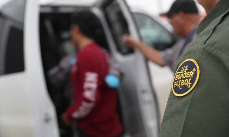 blog picture of border patrol agents taking in undocumented person
